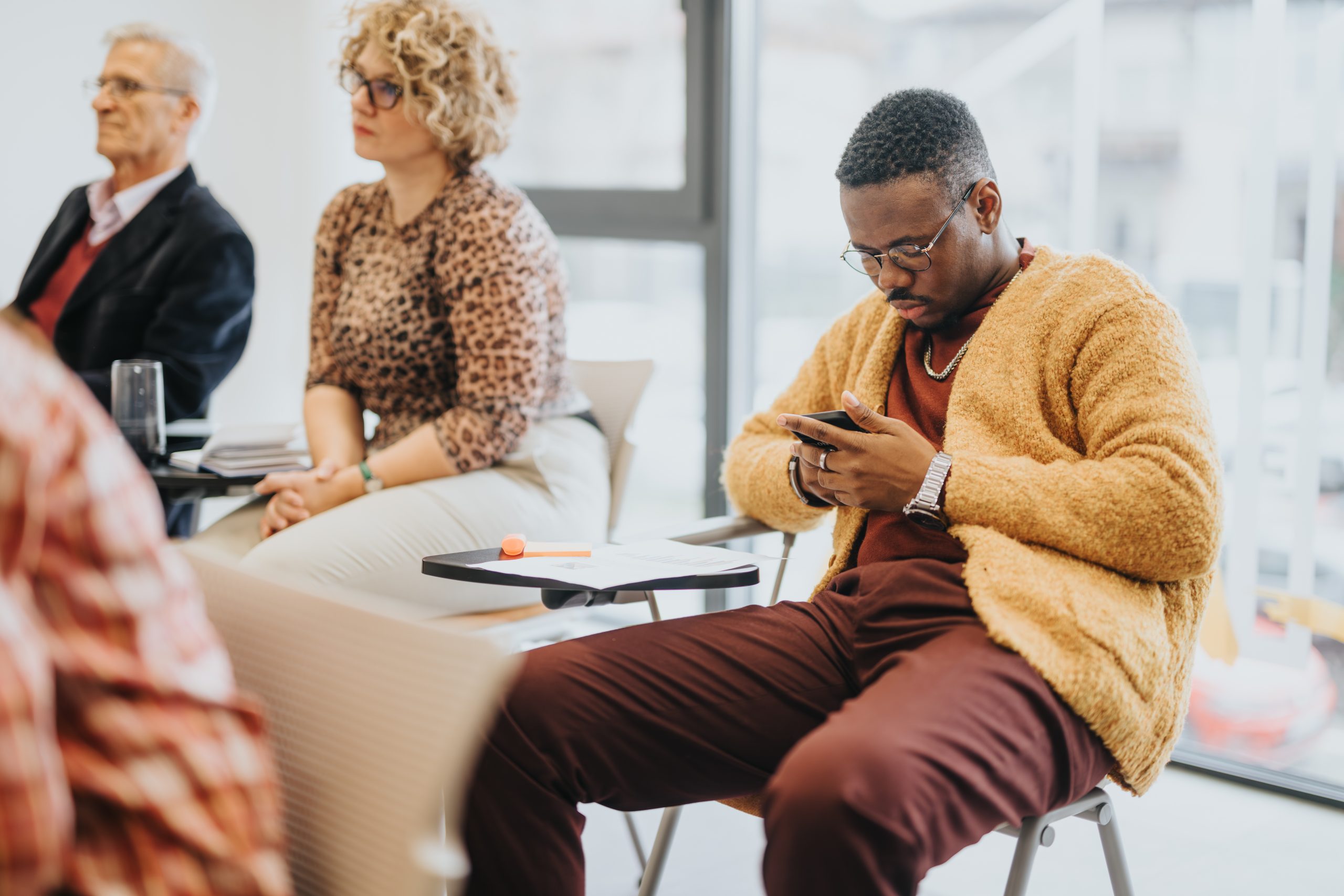 Deelnemer aan een PE-cursus die op zijn telefoon kijkt terwijl de training doorgaat